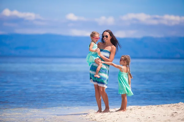 Adorable little girls and young mother on tropical white beach in desert island