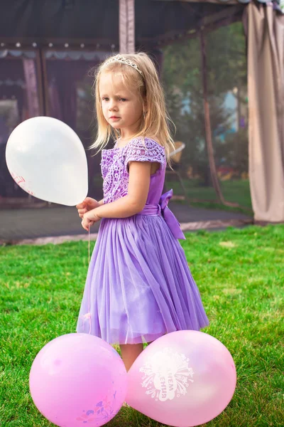 Little elegant girl on holiday with balloons