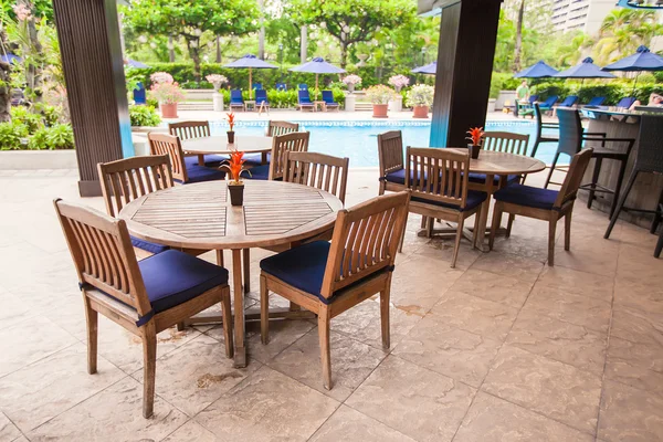 Hotel outdoor cafe with white table and chairs near pool