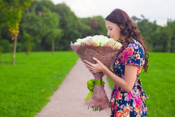 Beautiful young woman with big bouquet of white roses