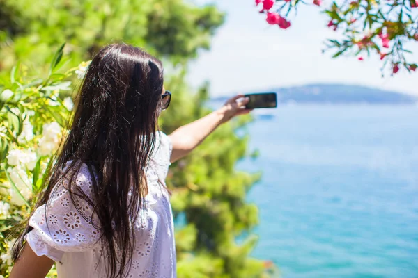 Back view of tourist woman taking photo with phone on beautiful bay