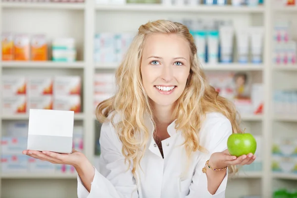 Female Pharmacist Holding Pill Box And An Apple