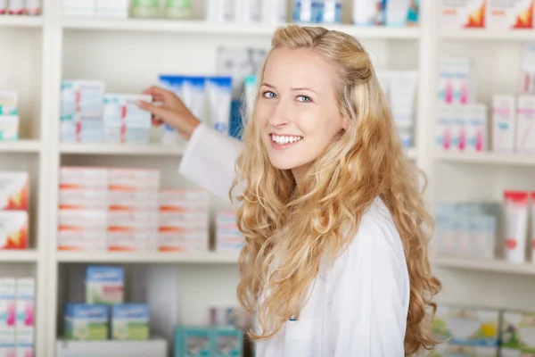 Female Pharmacist Taking Medicine From Shelf