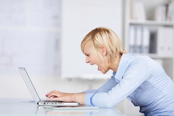 Angry Businesswoman Using Laptop While Screaming At Des