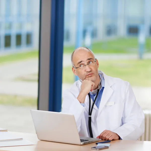 Thoughtful Doctor With Laptop On Desk