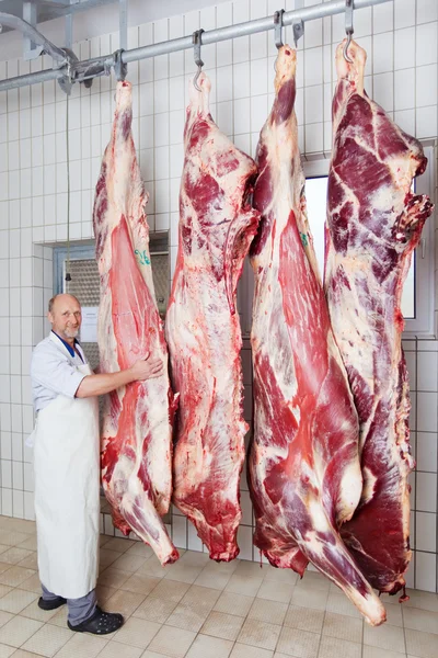 Butcher posing with peeled bodies of cow