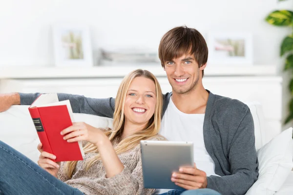 Laughing couple reading book and ebook