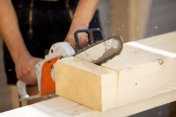 Carpenter saws a wood beam