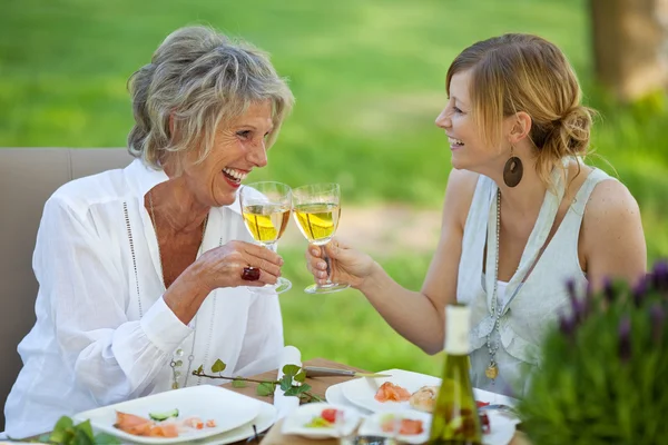 Mother And Daughter Toasting White Wine At Dining Table