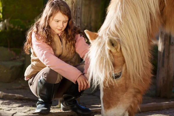 Girl observing a horse feeding — Stock Photo #26298013