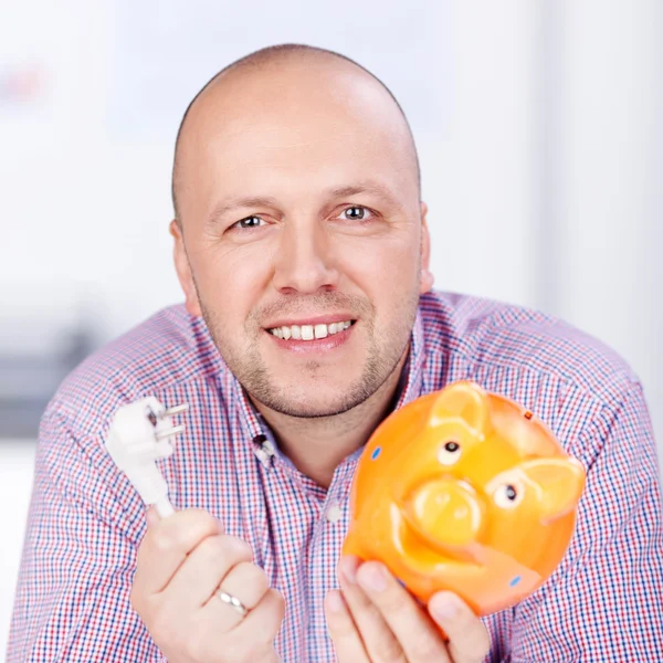 Businessman Holding Piggybank And Electric Plug In Office — Stock Photo #26475983