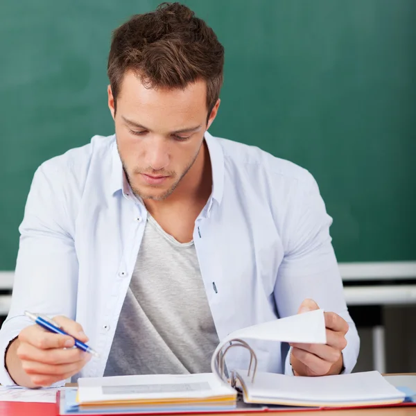 Thoughtful Man With Folder In Front Of Chalkboard