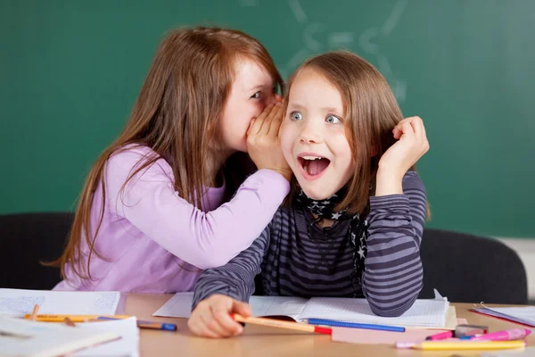 Two girls whispering in class