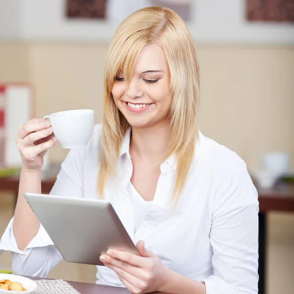 Businesswoman Using Digital Tablet While Having Coffee At Table