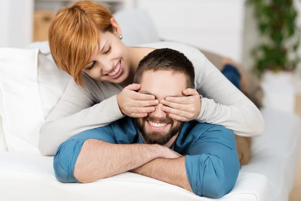 Woman Covering Mans Eyes While Lying On Sofa