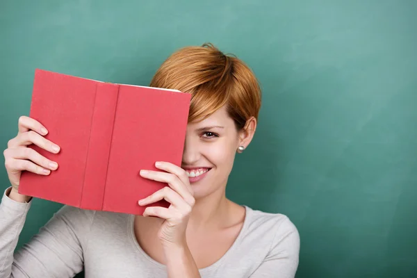Student Peeking Out Of Book Against Chalkboard