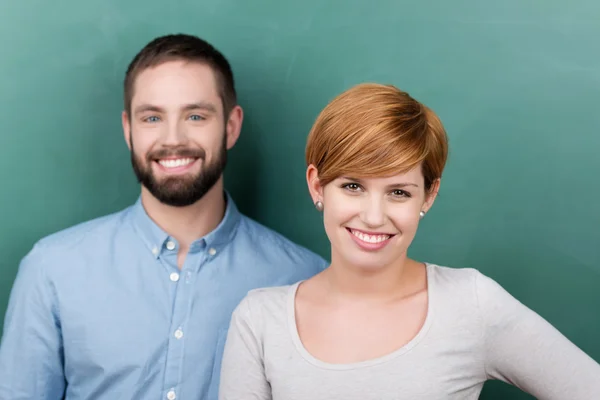 Male And Female Teachers Against Chalkboard