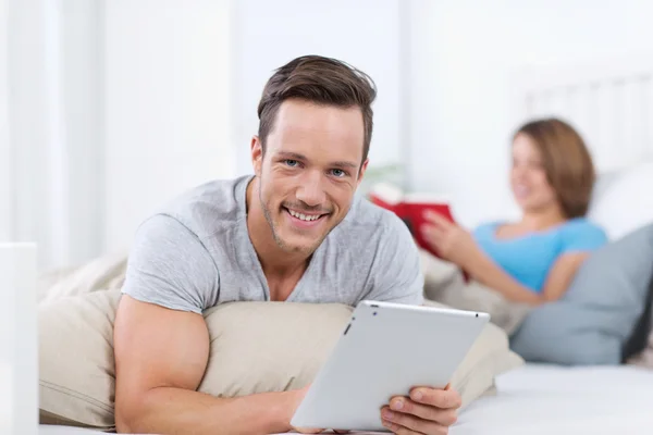 Smiling young man relaxing with a tablet-pc