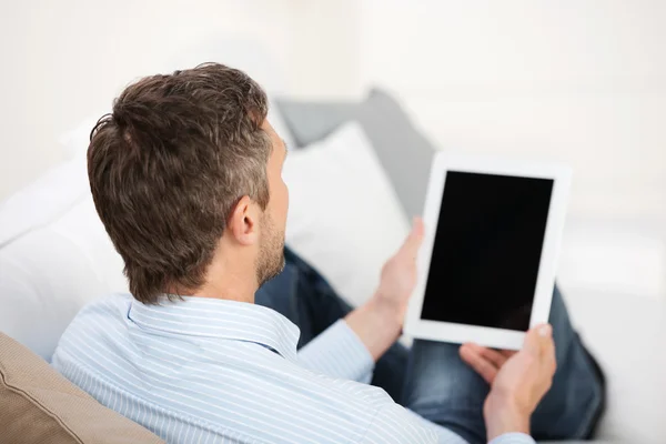 Rear View Of Mature Man Holding Digital Tablet On Sofa