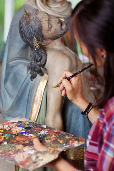 Woman Painting Jesus Christ's Statue With Paintbrush