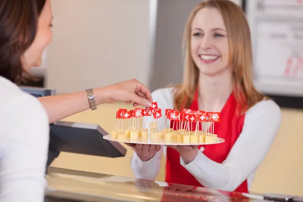 Saleswoman Offering Cheese Blocks With Swiss Flag To Customer