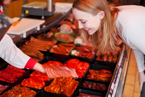 Woman Looking At Sliced Meat On Butcher Hand At Supermarket