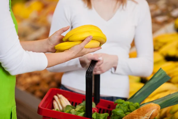 Female Worker Assisting Customer In Purchasing Bananas