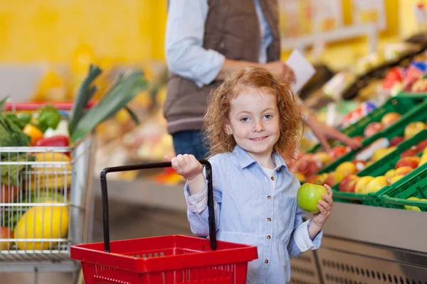 Girl Holding Shopping Basket And Apple At Grocery Store