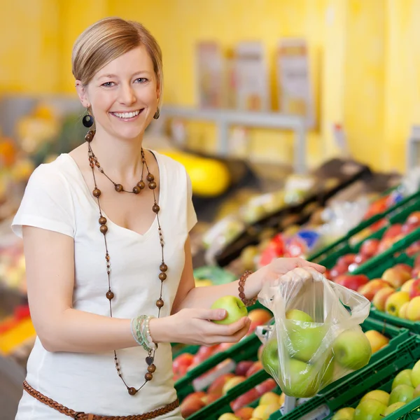 Woman Filling Plastic Bag With Apples In Grocery Store