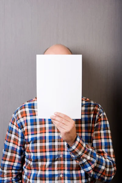 Balding man holding a blank paper in front of face