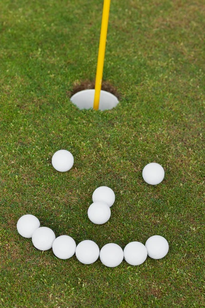 Smiley Face Made Of Golf Balls On Grassy Field