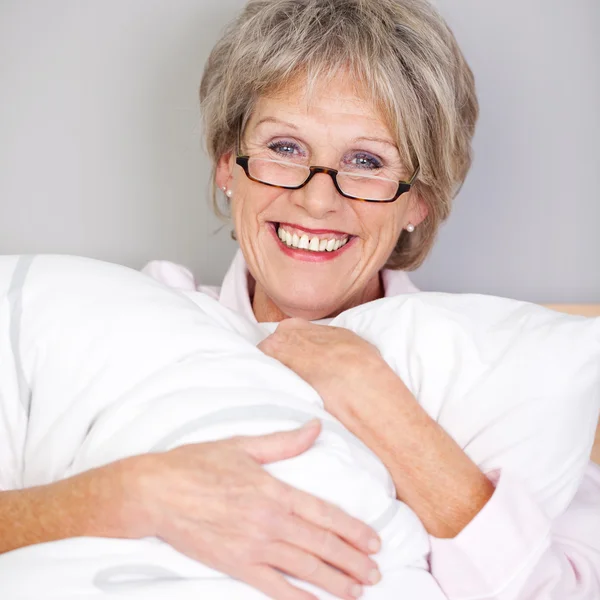 Senior Woman Embracing Pillow