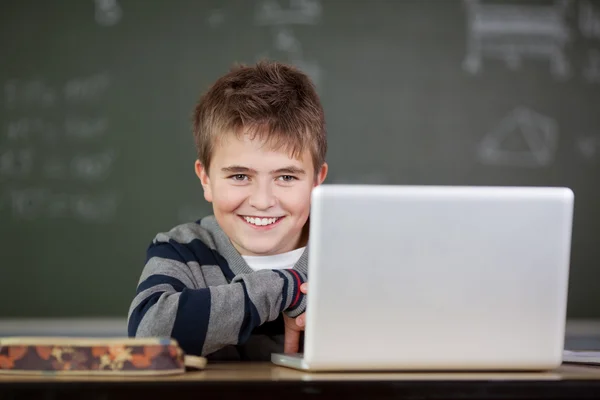 Student Smiling With Laptop On Desk In Classroom
