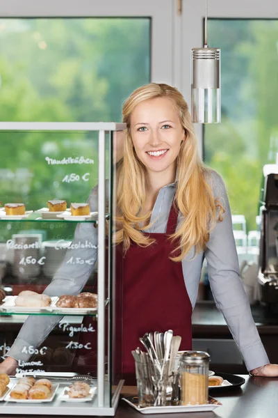 Smiling waitress leaning on coffee shop counter