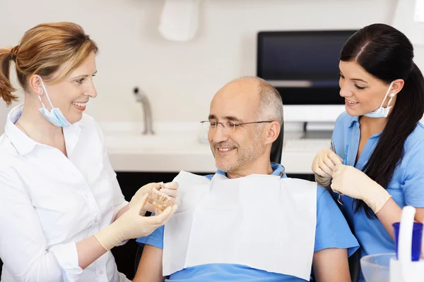 Dentist Explaining Teeth Model To Male Patient