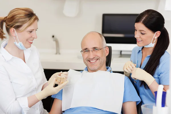 Dentist Explaining Teeth Model To Smiling Male Patient