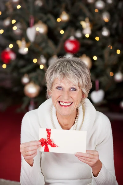 Smiling senior lady with a gift voucher