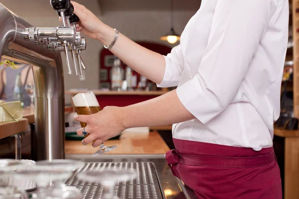 Woman dispensing draft beer in a bar