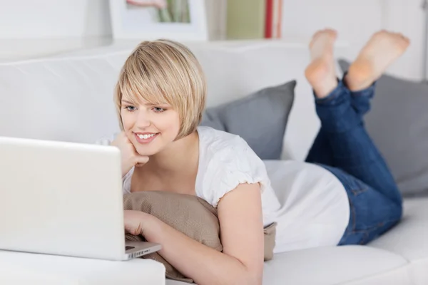 Woman relaxing on a sofa with a laptop