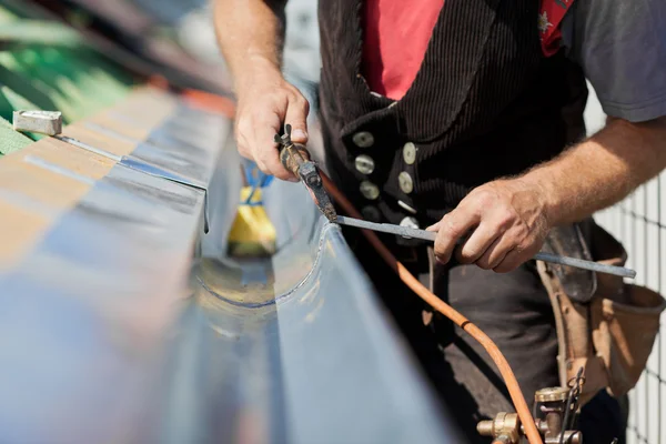 Close-up of a roofer applying weld into the gutter