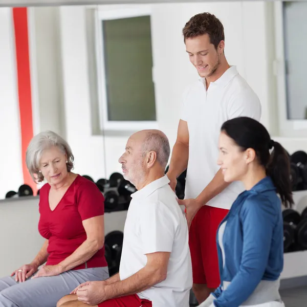 Trainer correcting the posture of an elderly man