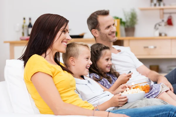 Happy young family watching television — Stock Photo #34572625
