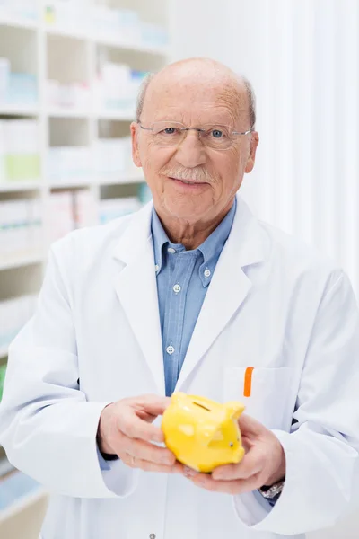 Successful pharmacist holding a piggy bank