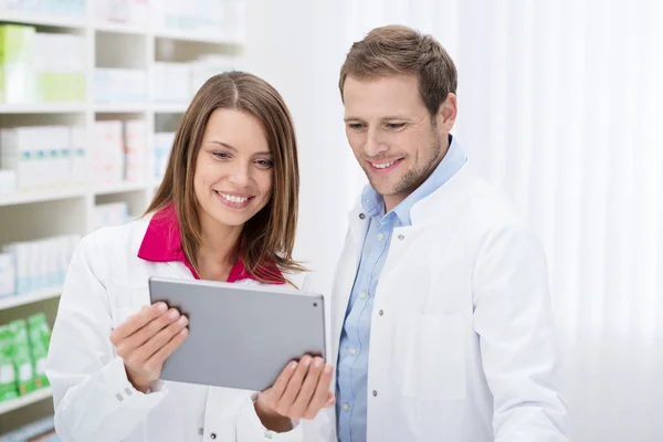 Two pharmacists check information on a tablet