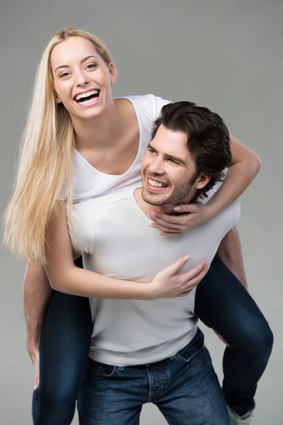 Young couple having fun riding piggy back