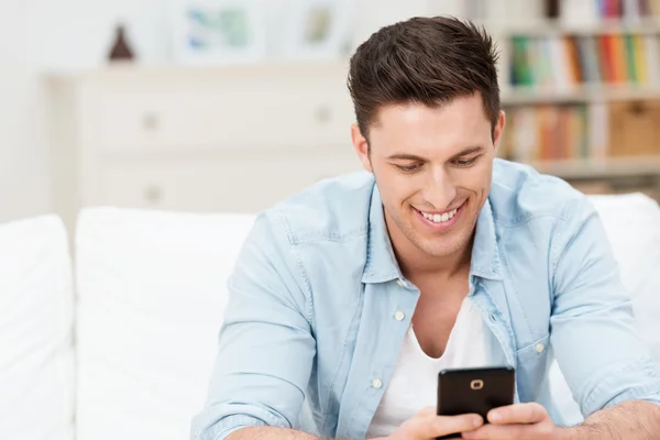 Man smiling ad he reads a message on his mobile