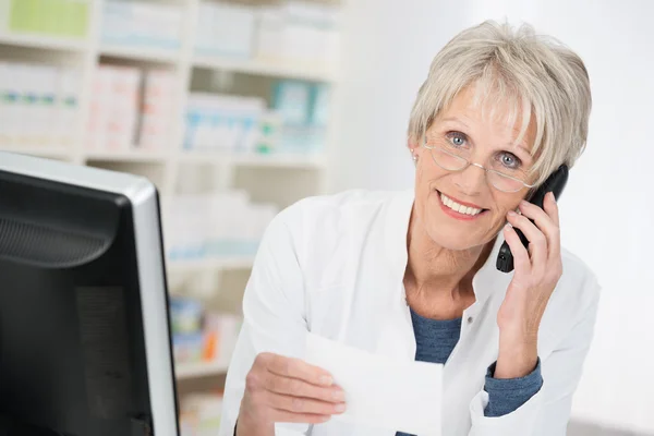 Smiling pharmacist checking up on a prescription