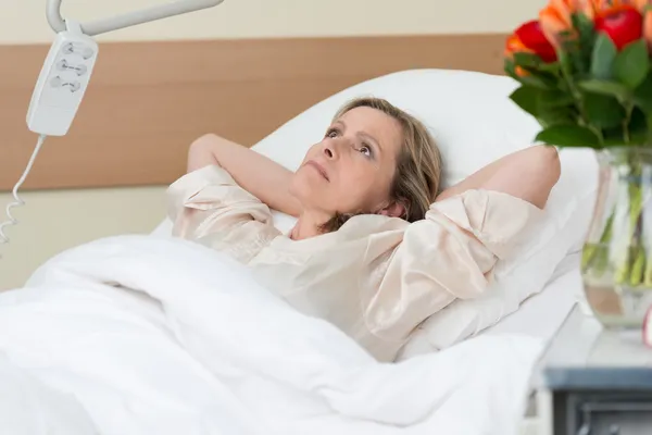 Worried woman lying thinking in hospital