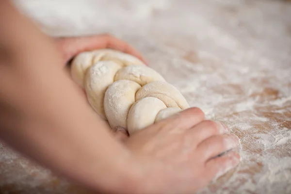 Chef's hands holding twisted dough