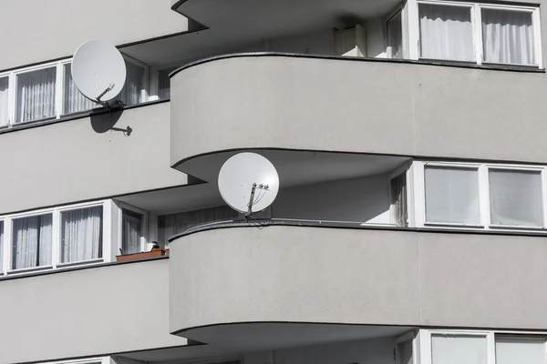 Detail of a sparse gray house with two  satellite dishes